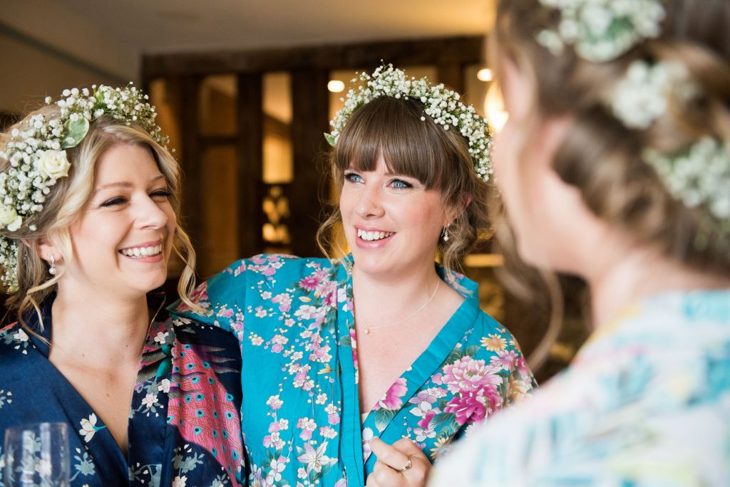 Smiling bride with bridesmaids wearing floral robes and boho Gypsophila crowns