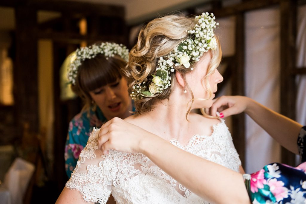 Bride wearing lace dress with floral crown during bridal prep Cornwall