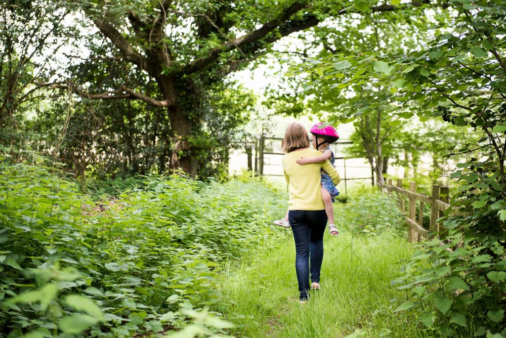 Mum carries daughter garden walk 