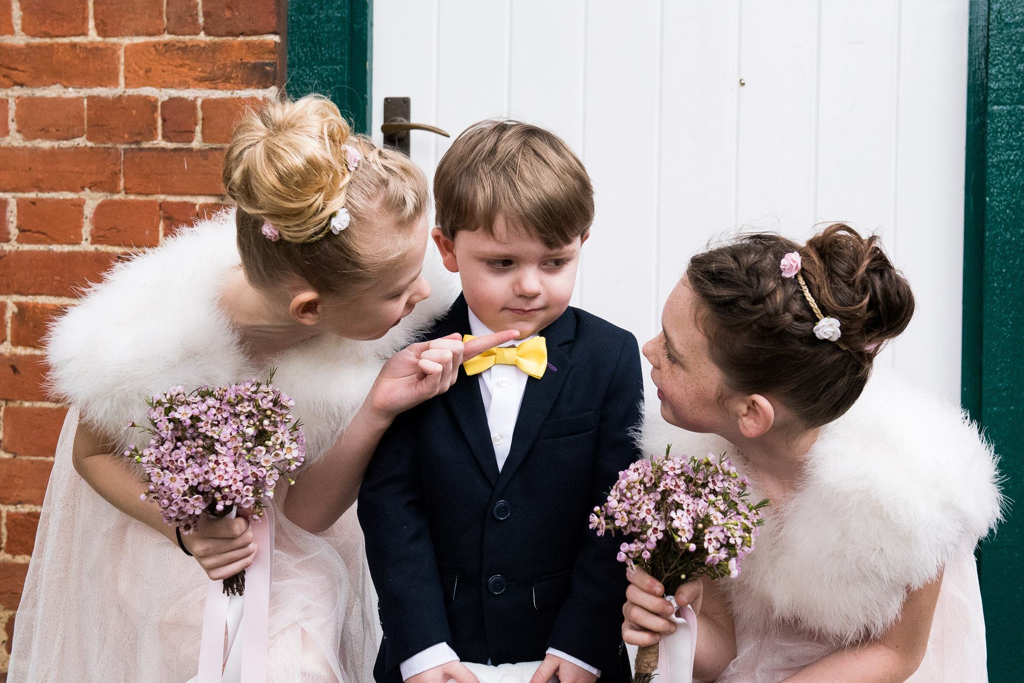 Flower girls trying to convince the ring bearer to smile