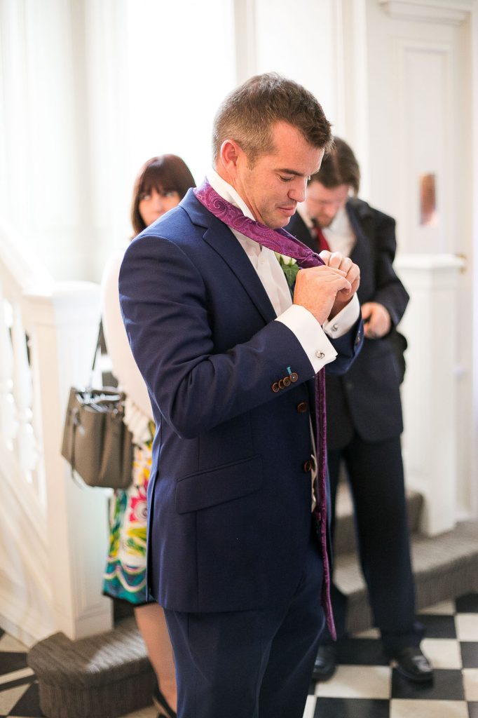 Groom putting finishing touches to his suit Surrey wedding 