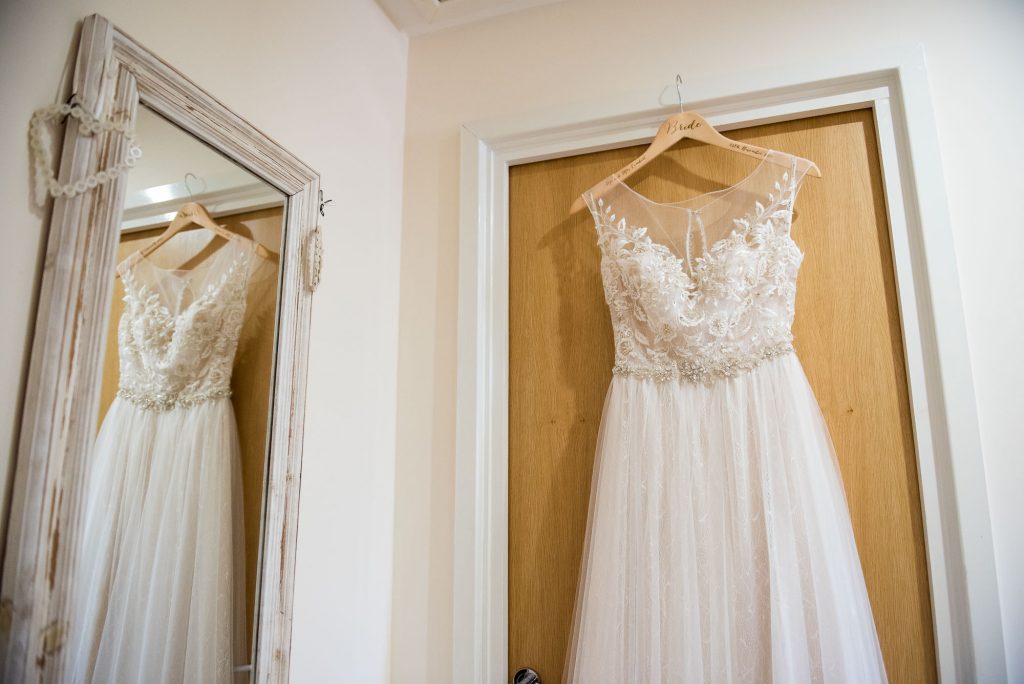 Ashridge House Wedding. Natural Wedding Photography. Bridal preparation Berkhamstead Brides dress hanging in doorway.