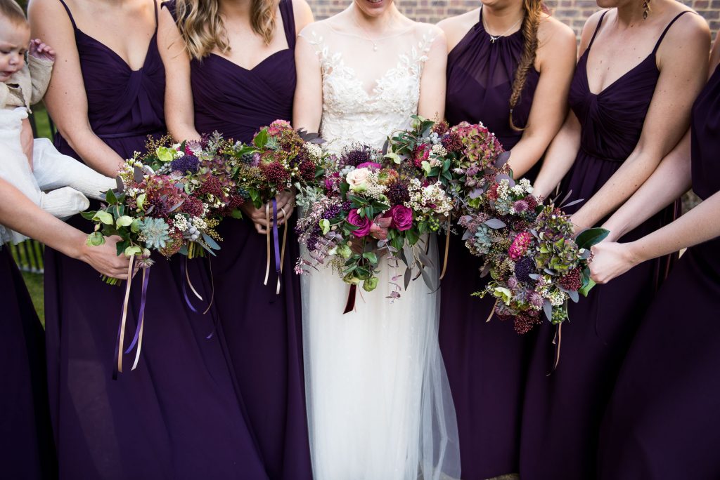 Ashridge House Wedding. Natural Wedding Photography. Bride surrounded by her bridesmaids with Winter wedding purple colours. Bouquets by Myrtle and Bloom.