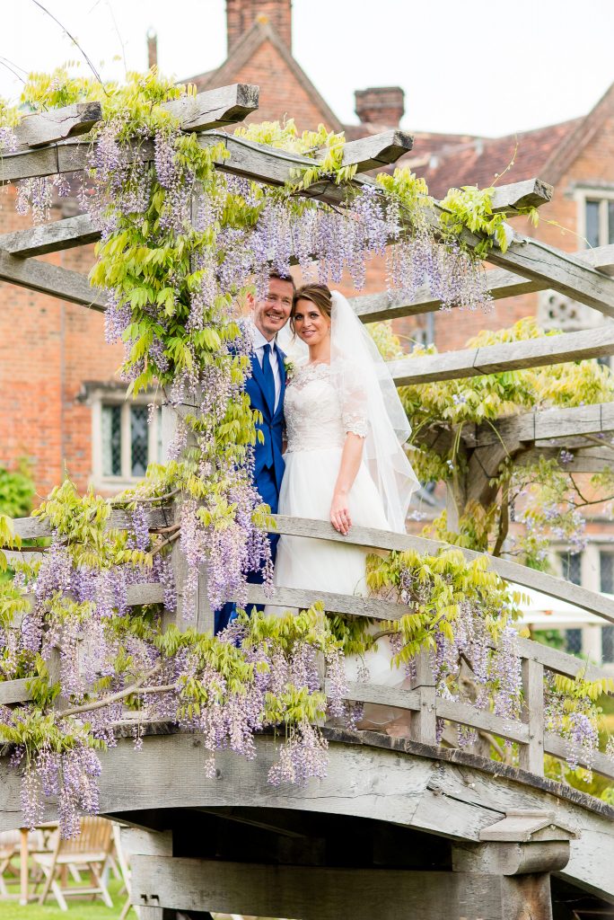 Great Fosters. Natural Wedding Photography Surrey. Couple embrace on the old wooden wisteria bridge at Great Fosters.