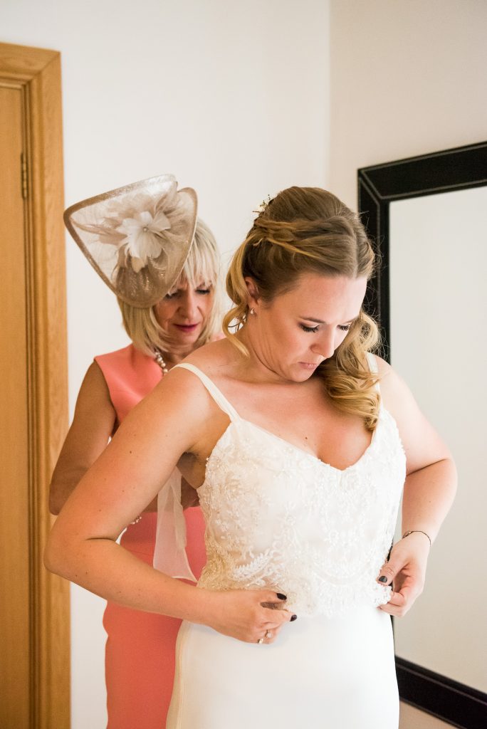 Mother Of The Bride Helps Her Daughter Into Catherine Deane Bridal Dress