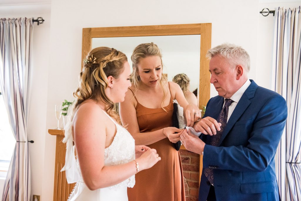 Bride and Her Sister Help Their Dad With His Cufflinks 