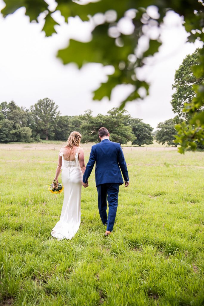 Bride and Groom Walk Together In A Field