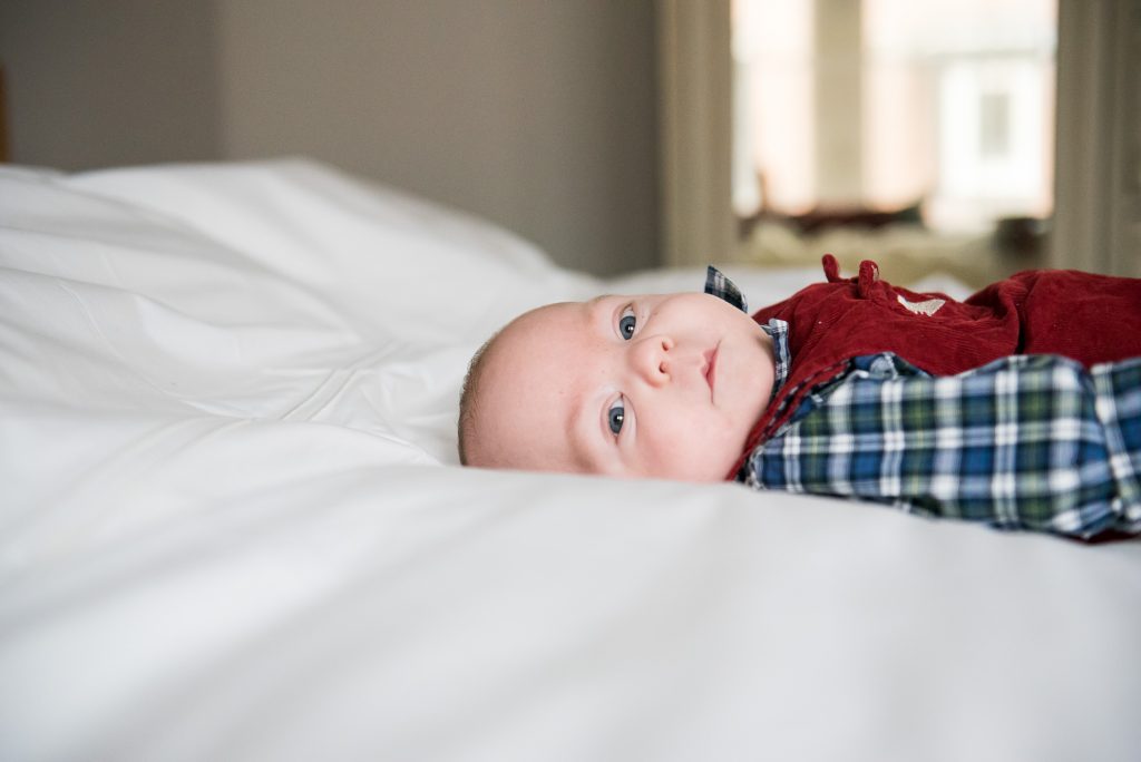 Newborn Photography Guildford, Christmas Family Shoot, Baby On The Bed Looking To Camera