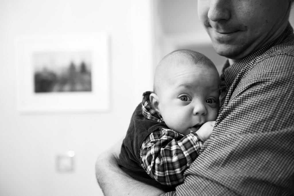 Newborn Photography Guildford, Christmas Family Shoot, Black and White Photograph of Baby Cuddling on Fathers Chest