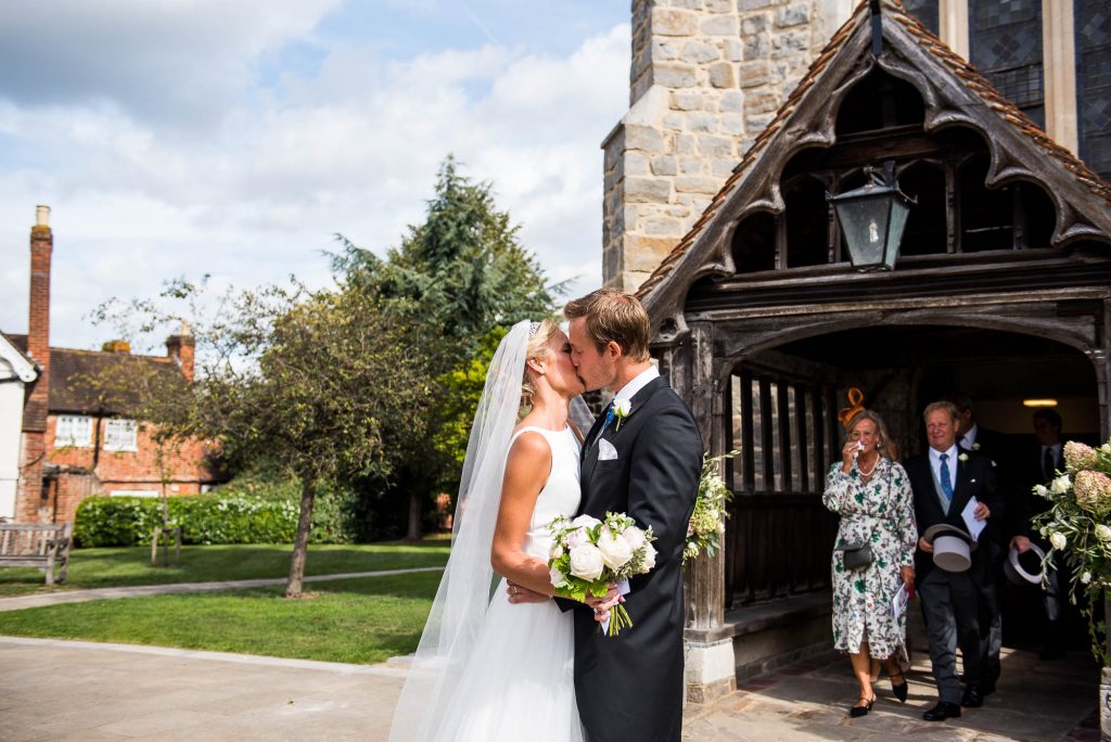 Outdoor Wedding Photography Surrey, Gorgeous Bride And Groom Share A Kiss Outside The Church