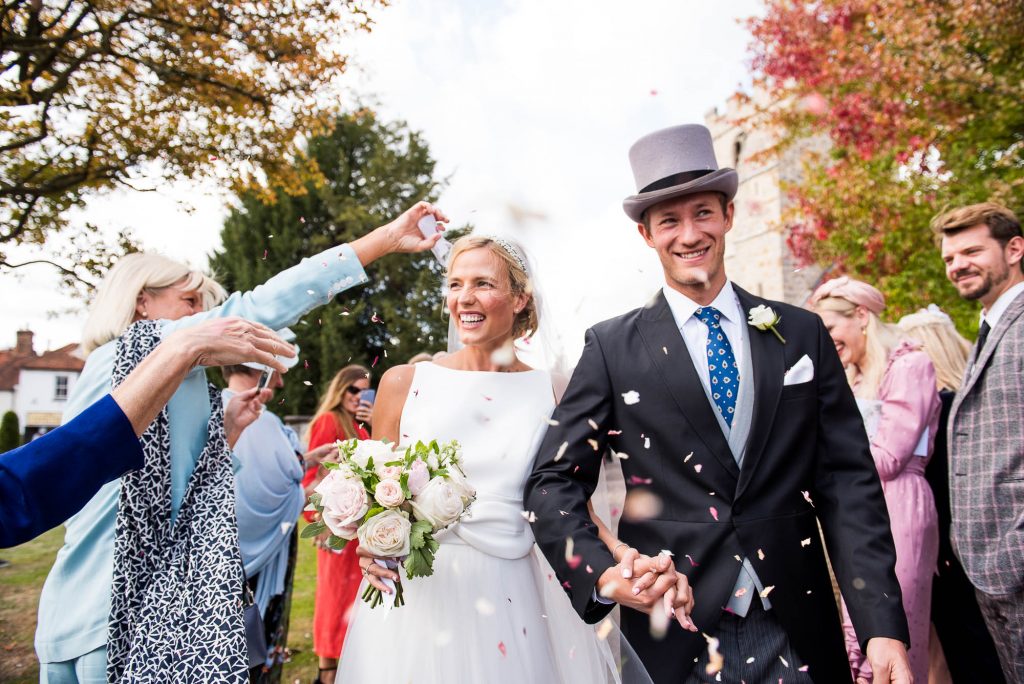 Outdoor Wedding Photography Surrey, Stunning Scandinavian Couple Smiling as They Walk Down The Confetti Line