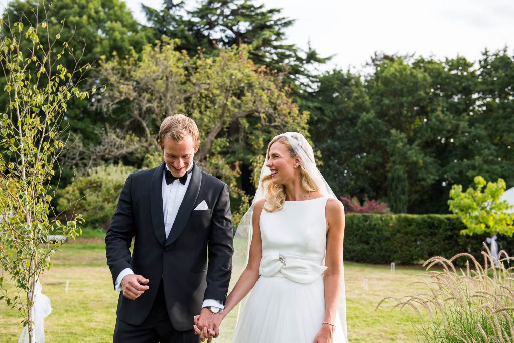 Outdoor Wedding Photography Surrey, Elegant Bride and Groom Smiling Naturally As They Walk Together