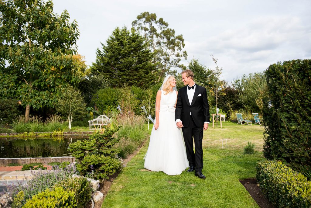 Outdoor Wedding Photography Surrey, Stylish Couple Walking Naturally Hand In Hand Smiling Naturally At Each Other