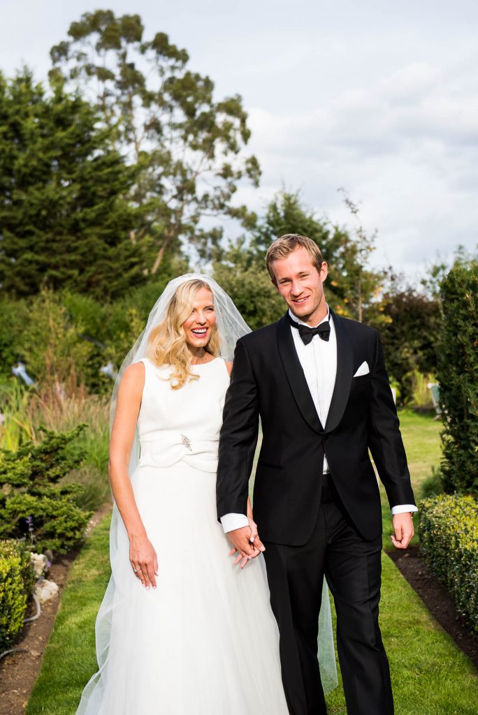 Outdoor Wedding Photography Surrey, Elegant Bride and Groom In Black Tie Dress Walking Together and Laughing