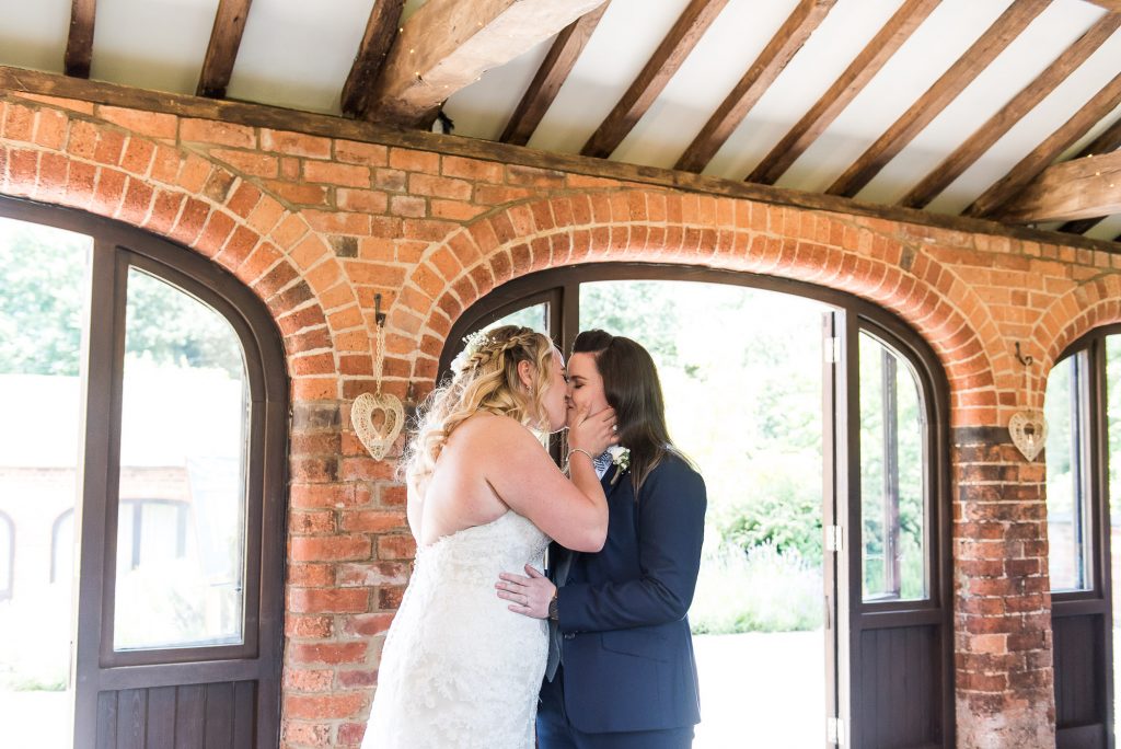 lgbt wedding photographer, brides share a passionate first kiss at their ceremony