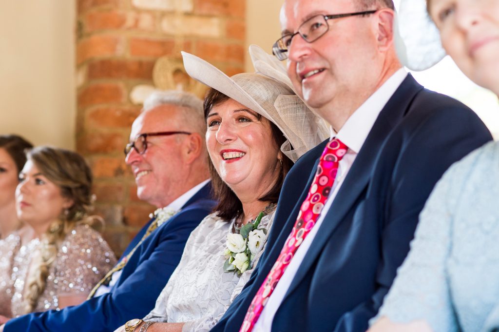 lgbt wedding photographer, Guests smile as brides marry at same sex ceremony 