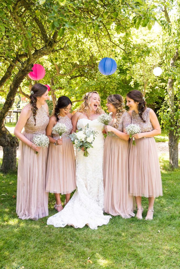 lgbt wedding photographer, beautiful bride laughs naturally with her bridesmaids under coloured lanterns