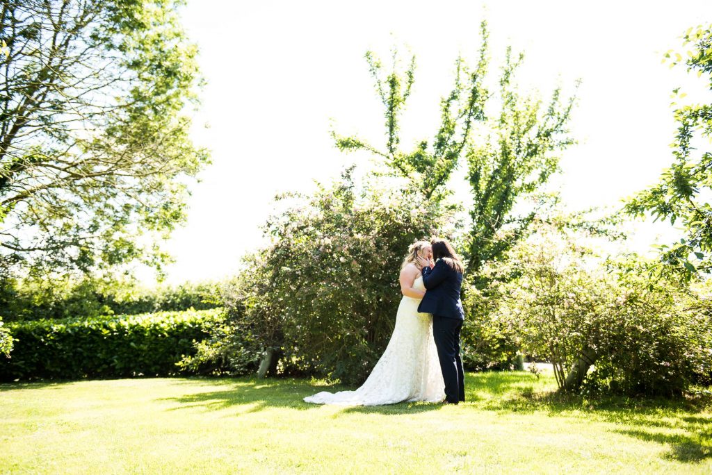 lgbt wedding photographer,  same sex couple embrace in the sunshine