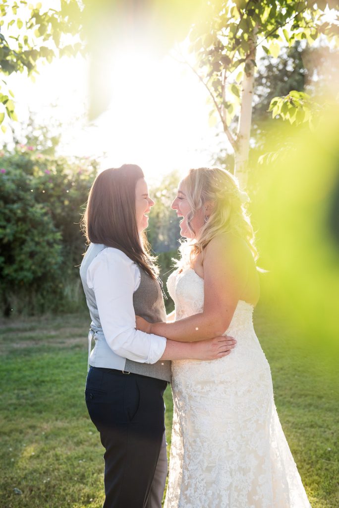 lgbt wedding photographer, same sex couple laugh together at sunset