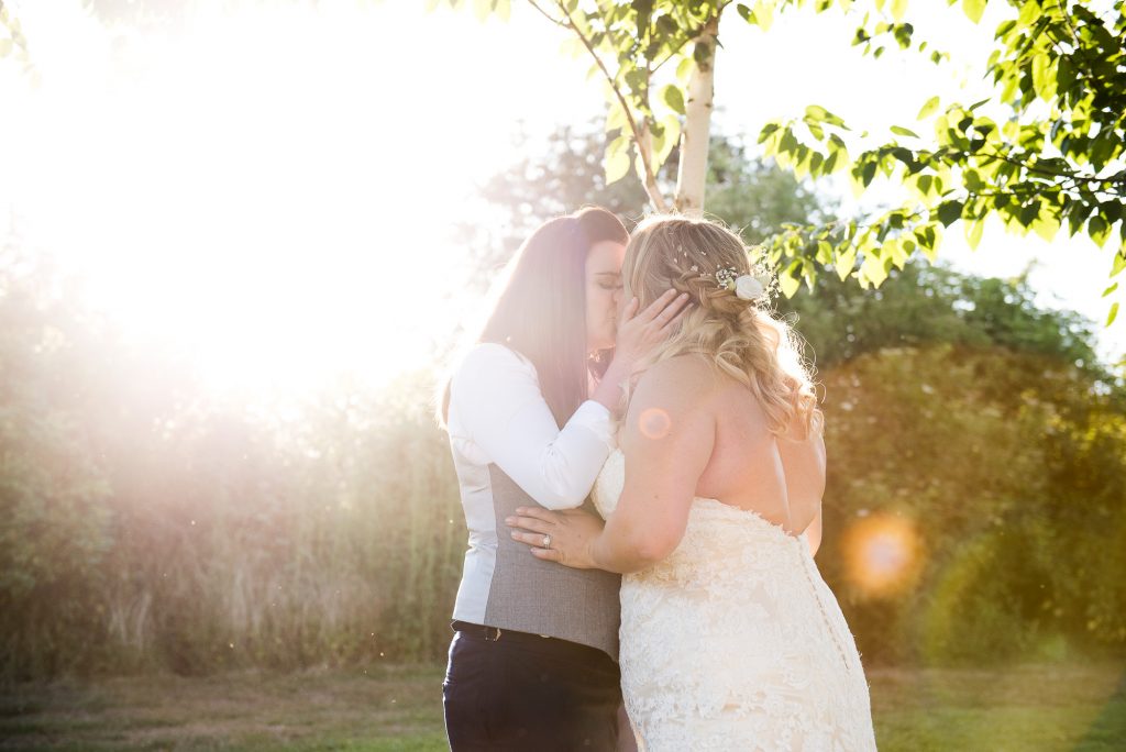 lgbt wedding photographer, brides share a kiss together at sunset