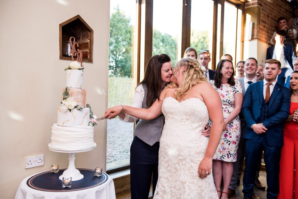 lgbt wedding photographer, same sex couple share a kiss as they cut the cake