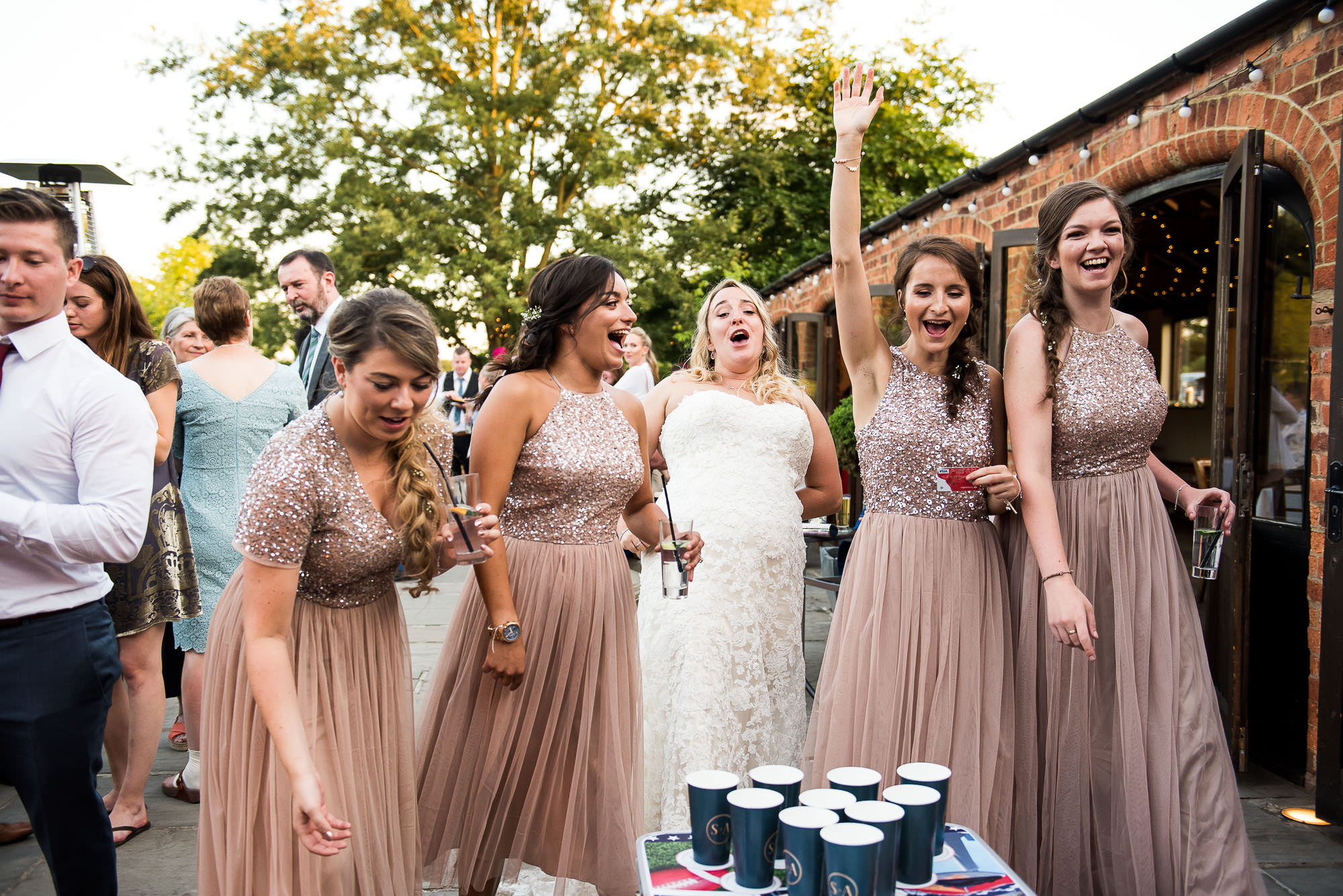 lgbt wedding photographer, bridal party in peach sequin dresses play beer pong at wedding reception