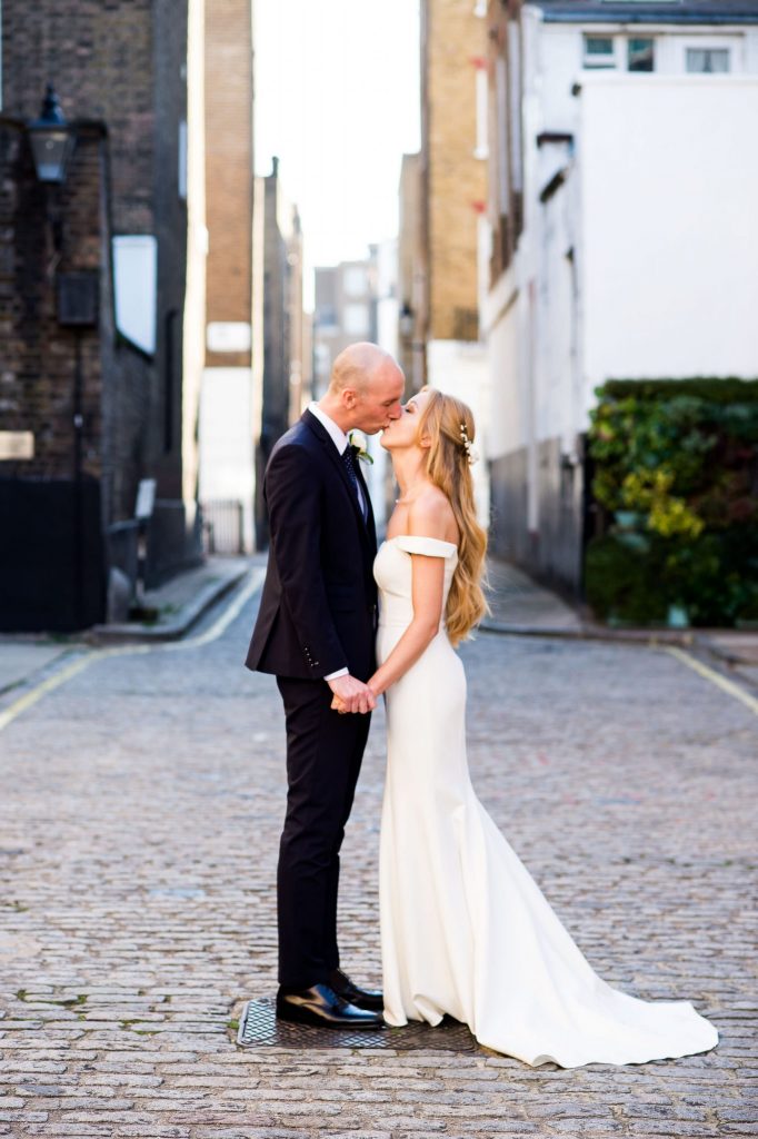 Old Marylebone Town Hall Wedding, bride and groom share a kiss in traditional London Mews street