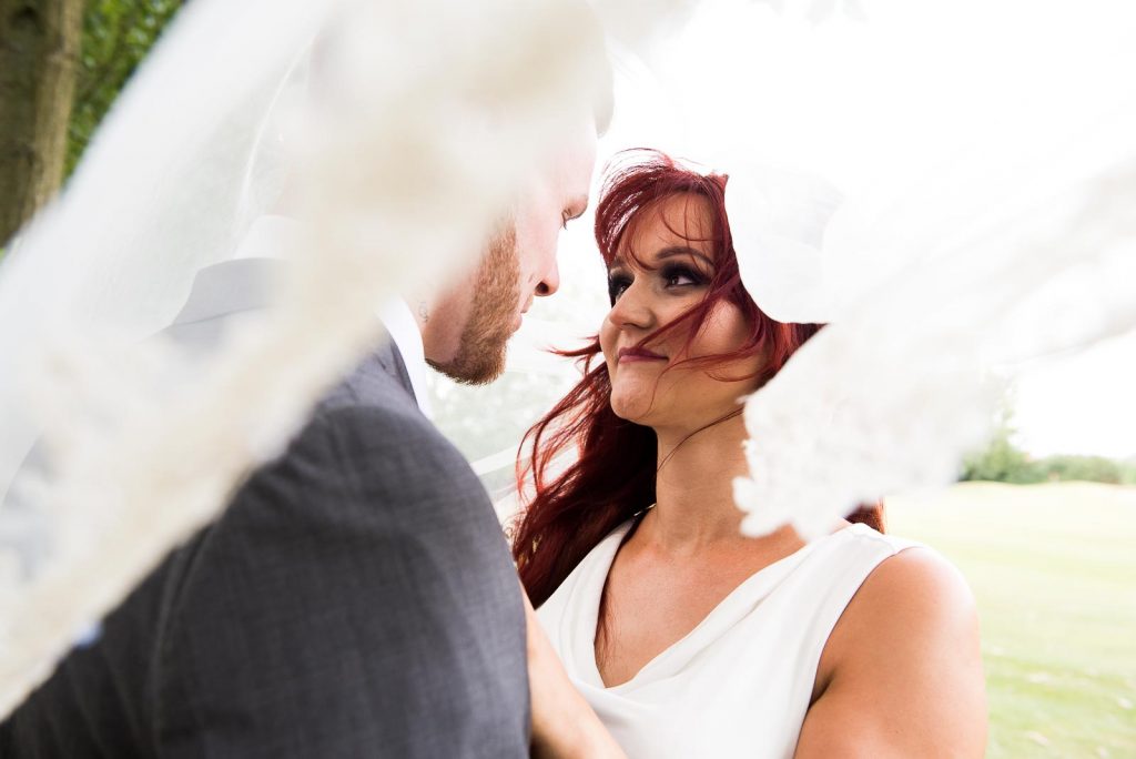 Alternative wedding photography - red haired bride and groom embrace under a veil