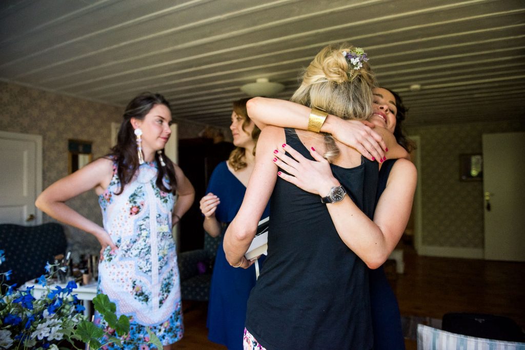 LGBT wedding photography, bride is embraced with hugs from her bridesmaids