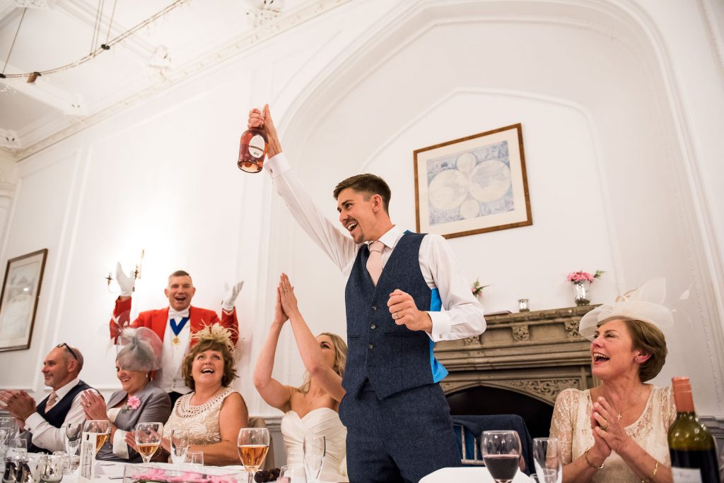 LGBT wedding photography, gay couple enbrace on the dance floor, groom raises a champagne bottle for wedding cheers