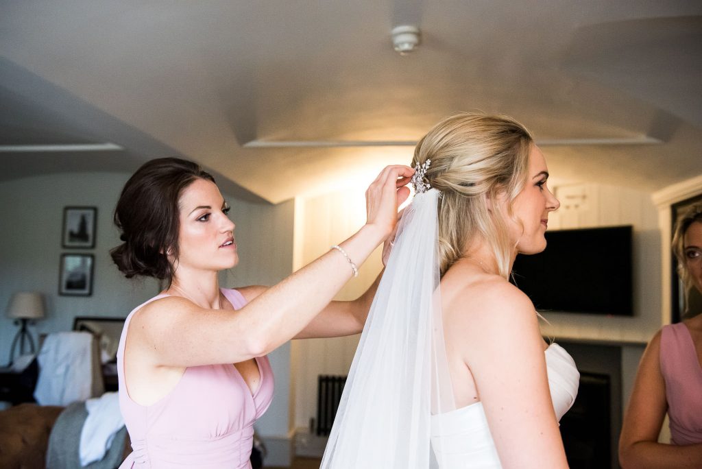 LGBT wedding photography, Surrey bride has veil attached by bridesmaid in bridal preparation photography