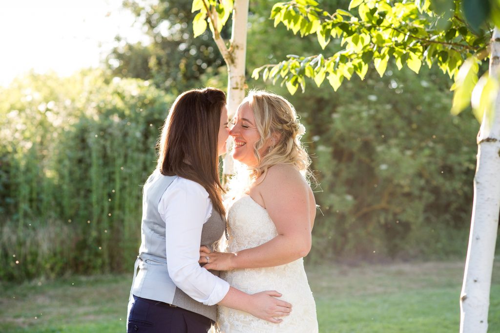 LGBT wedding photography, brides share a passionate kiss in the evening sunlight