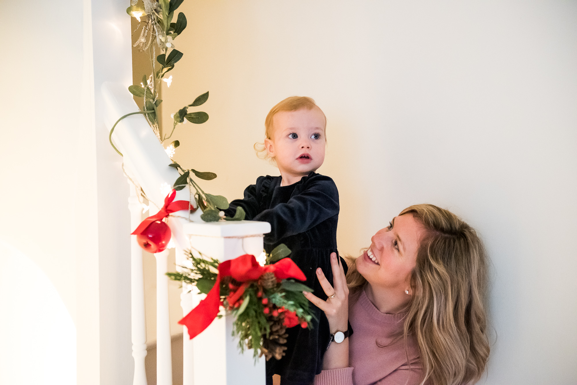 Mother and daughter sit on the stairs adorned with Christmas decorations