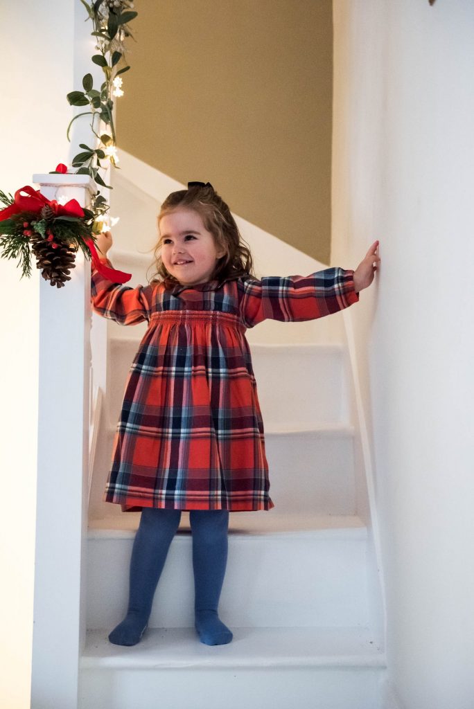 Little girl dressed in a tartan dress on the stairs