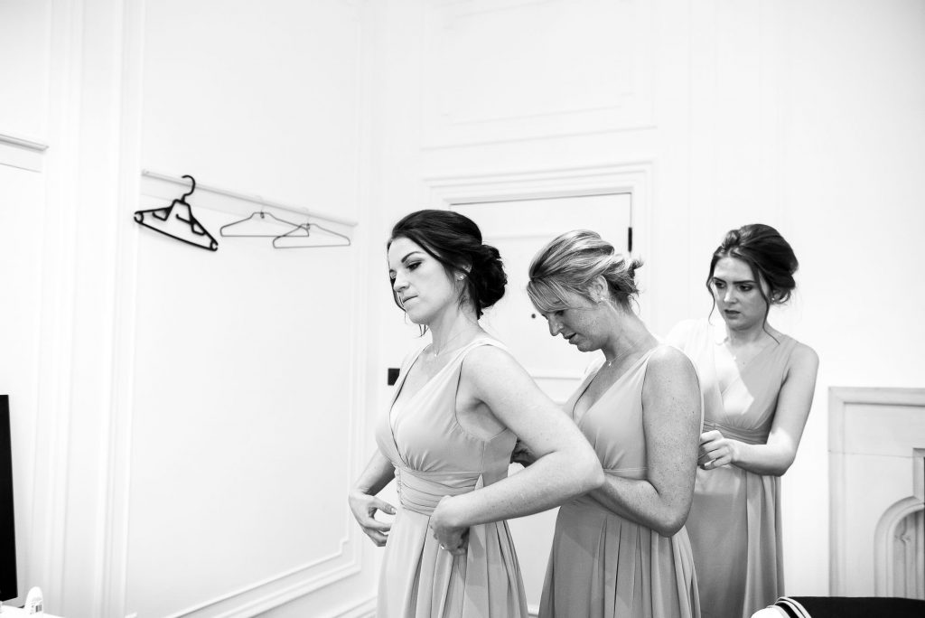 bridesmaids helping each other into dresses