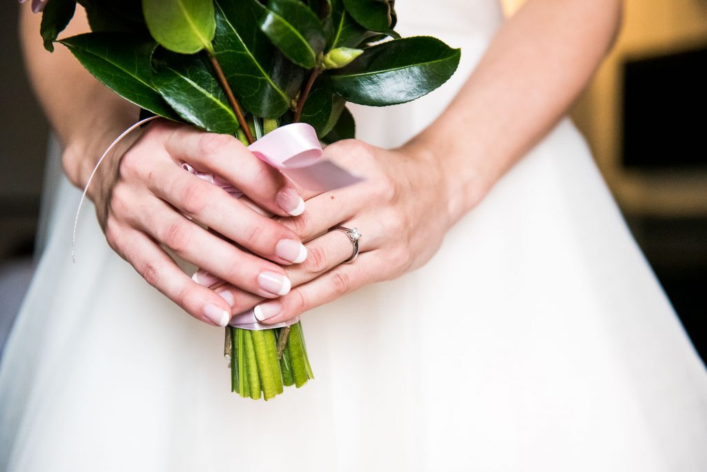 bride holds bouquet with engagement ring