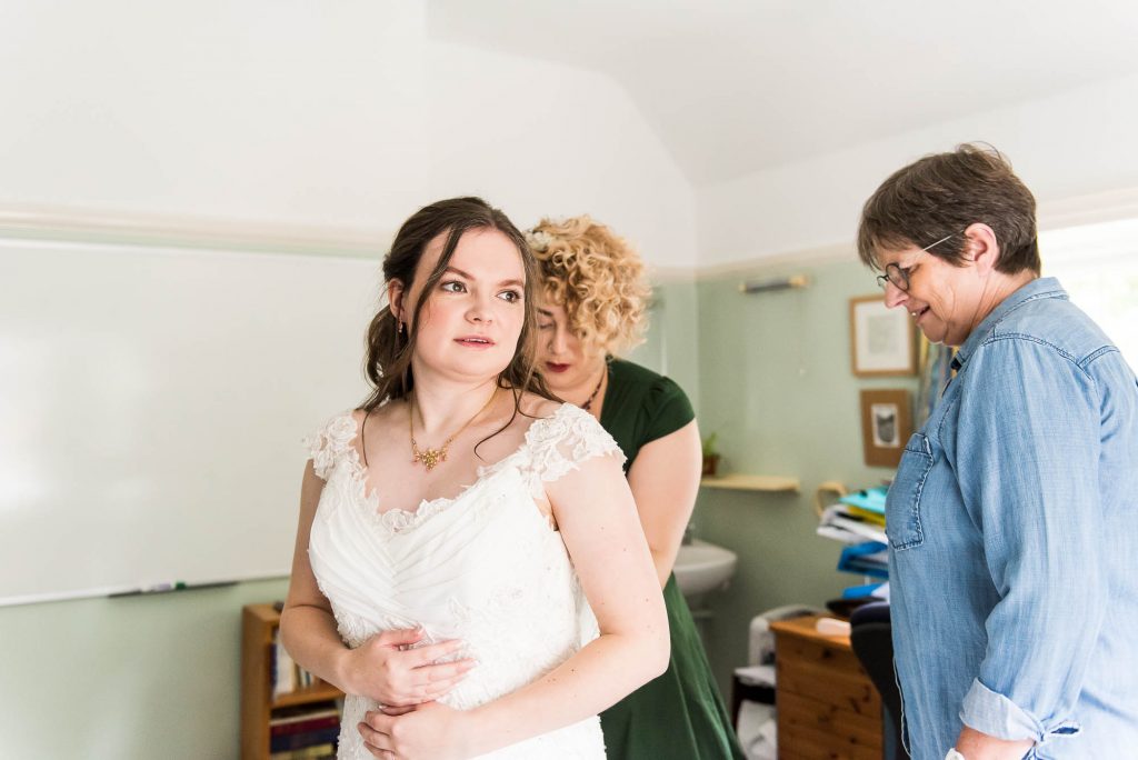 Surrey wedding as relaxed bride puts on her lace wedding dress, Documentary wedding photographer surrey