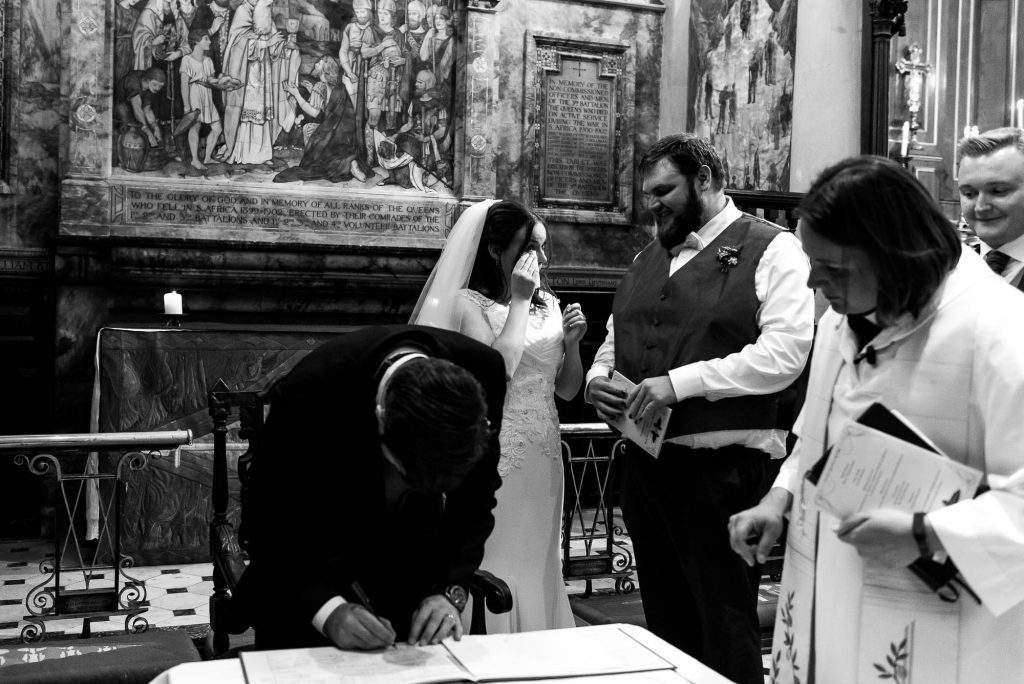 Candid and natural moment of the wedding party signing the register