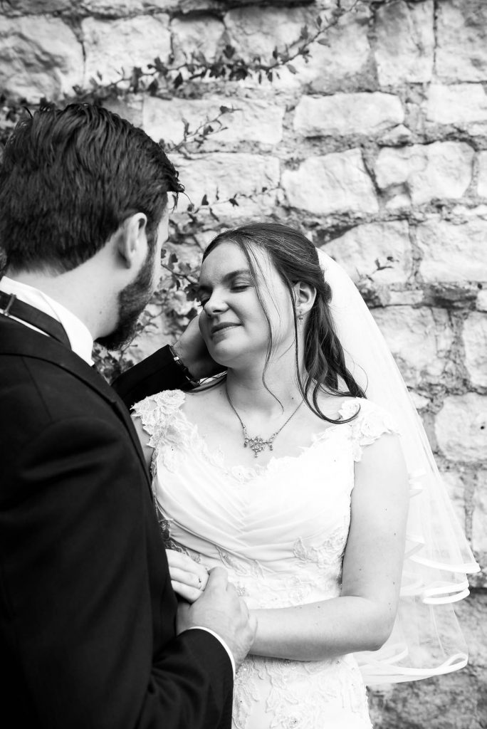 Black and white image of women with eyes closed and husband stroking her face, Documentary wedding photographer surrey