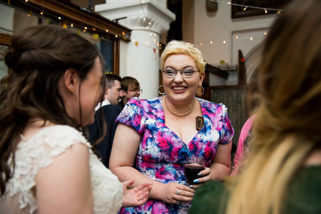 Woman with stylish short blonde hair and colourful dress chats with the bride