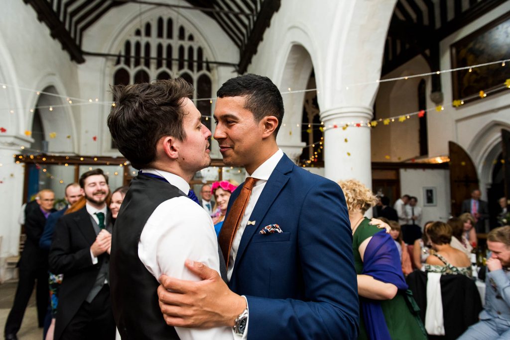 Gay couple share loving moment together on the dance floor. Documentary wedding photographer surrey