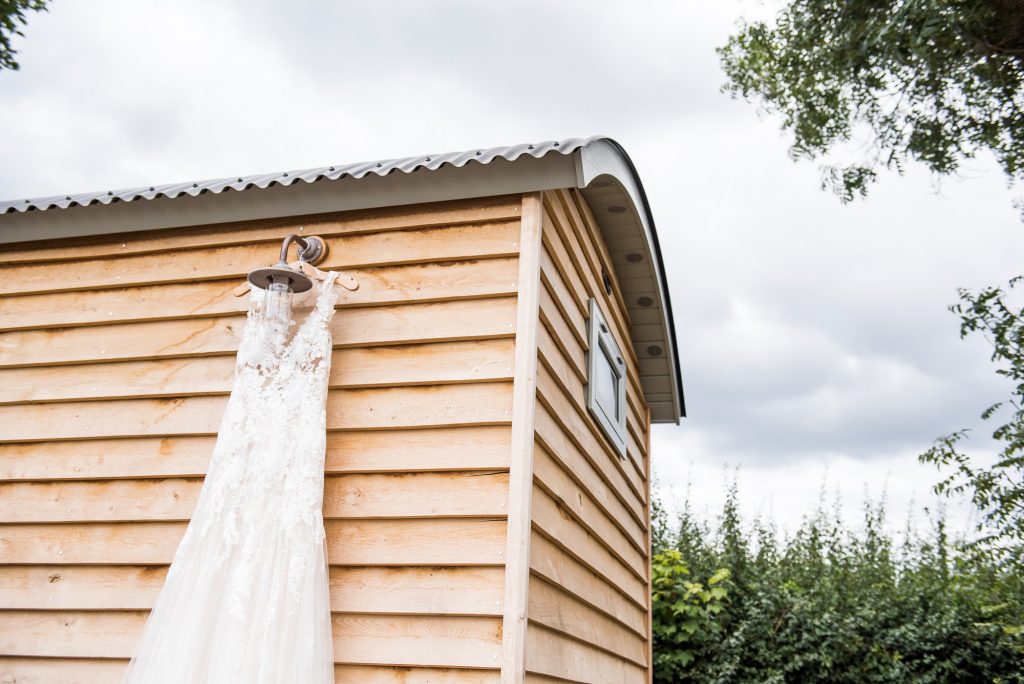 Lace wedding dress hangs on a shepherds hut