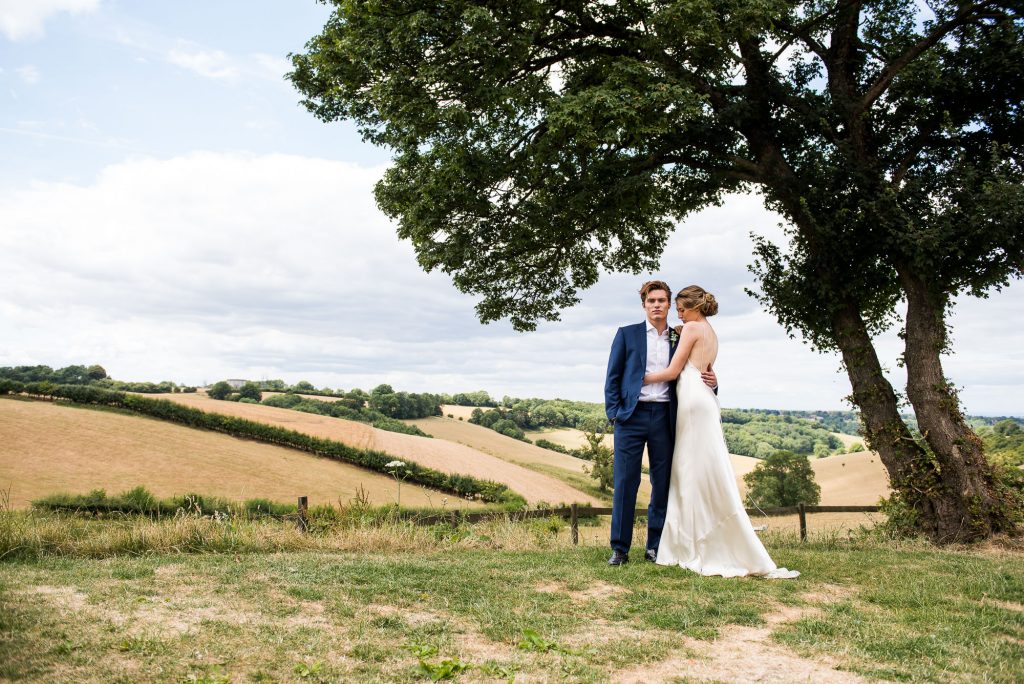 Botley Hill Barn wedding couple stand with the rolling countryside behind them