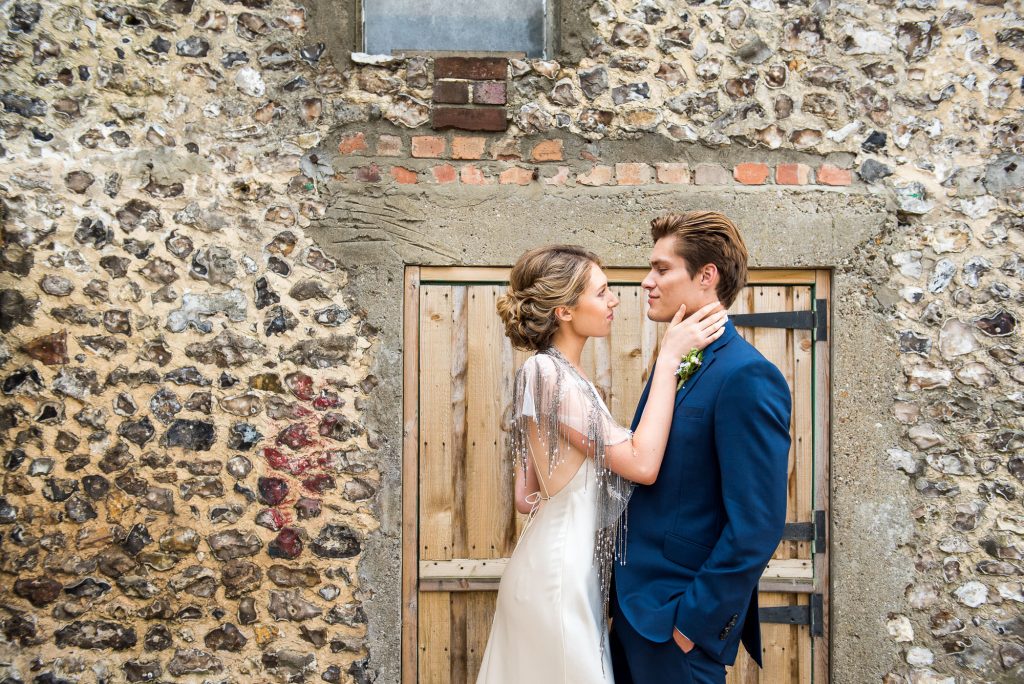 Couple embrace in front of rustic barn door 