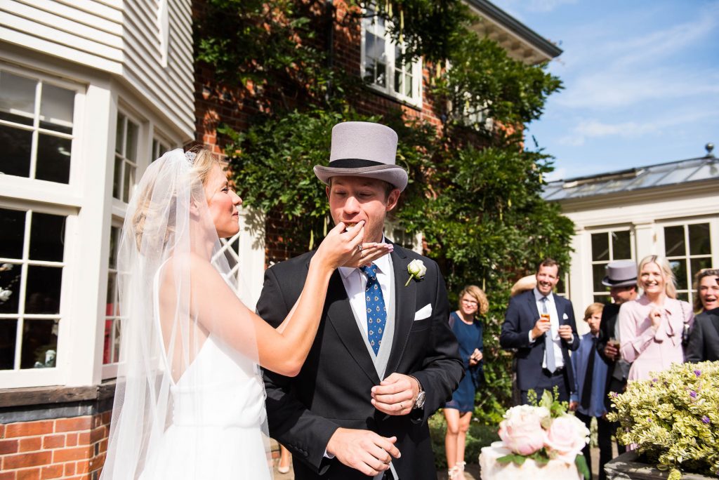 Danish wedding couple feed each other cake at an intimate wedding ceremony in Surrey