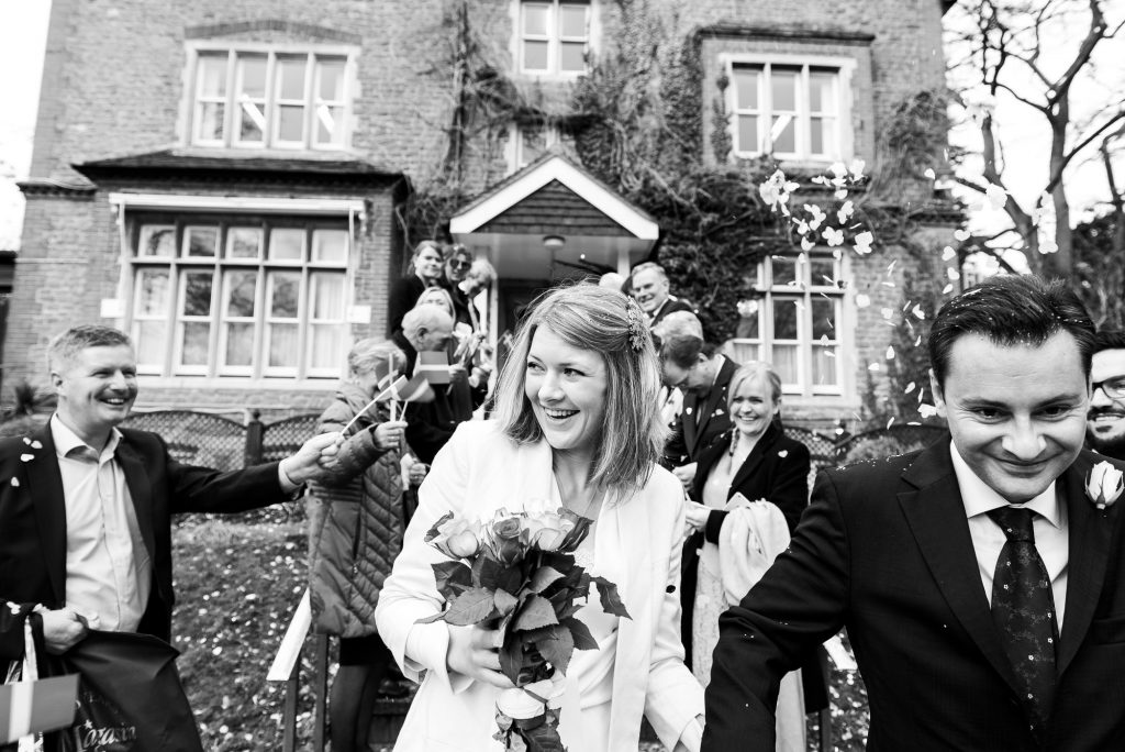 Black and white image of wedding couple exiting the confetti line