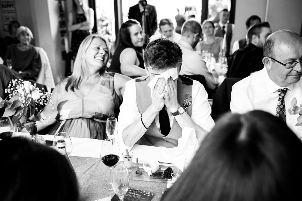 How to choose a wedding photographer // emotional guest hides his face in napkin during wedding speeches