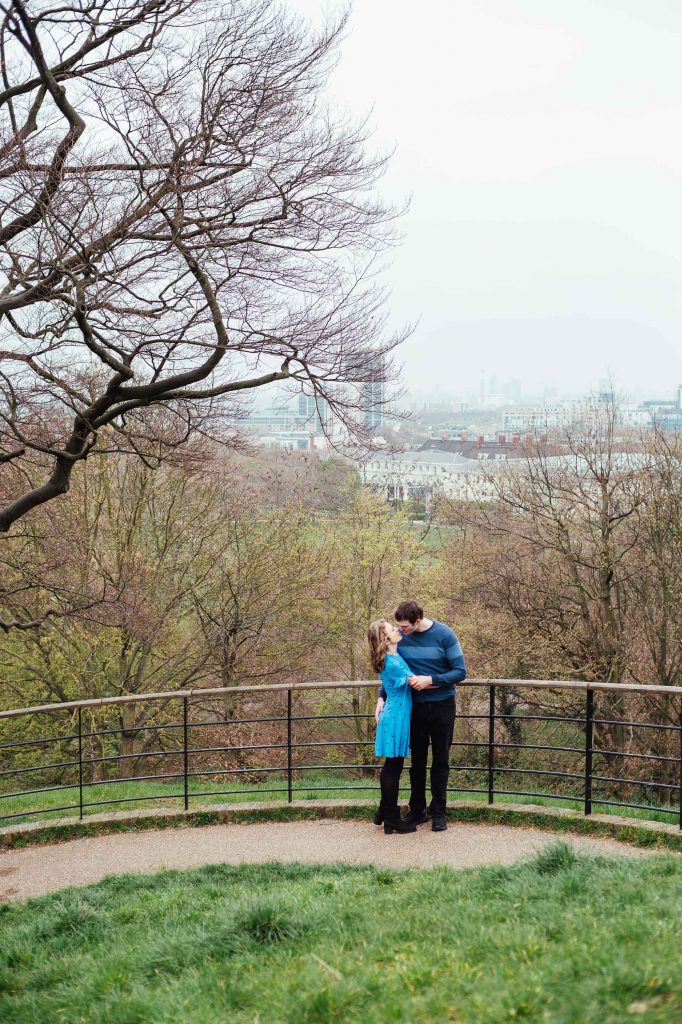 Engaged couple kiss with London city skyline as a backdrop