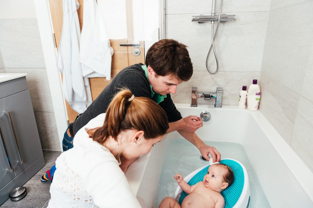 Parents bathe their baby girl in relaxed newborn photography shoot
