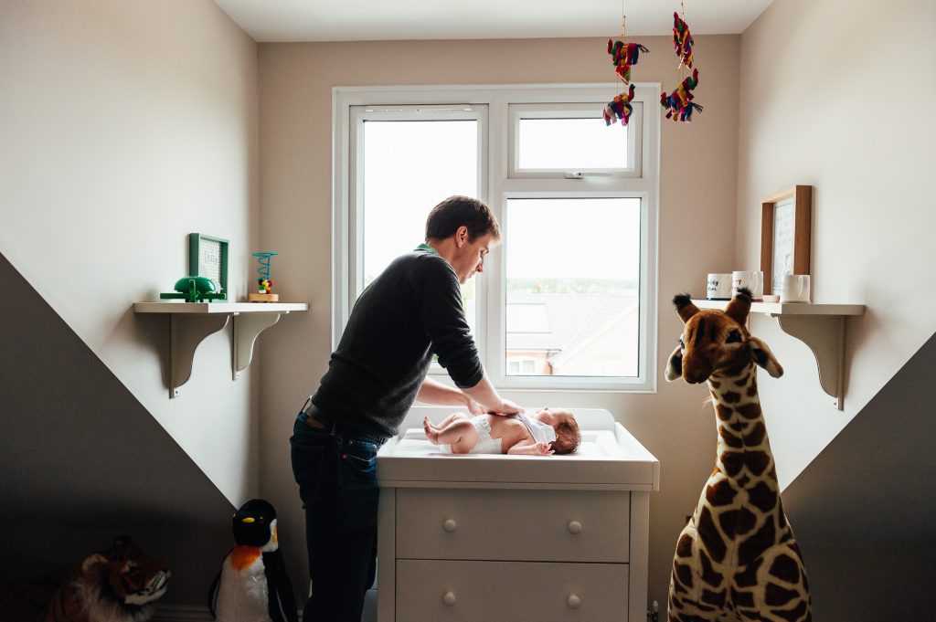 Father dressing his newborn baby at changing unit